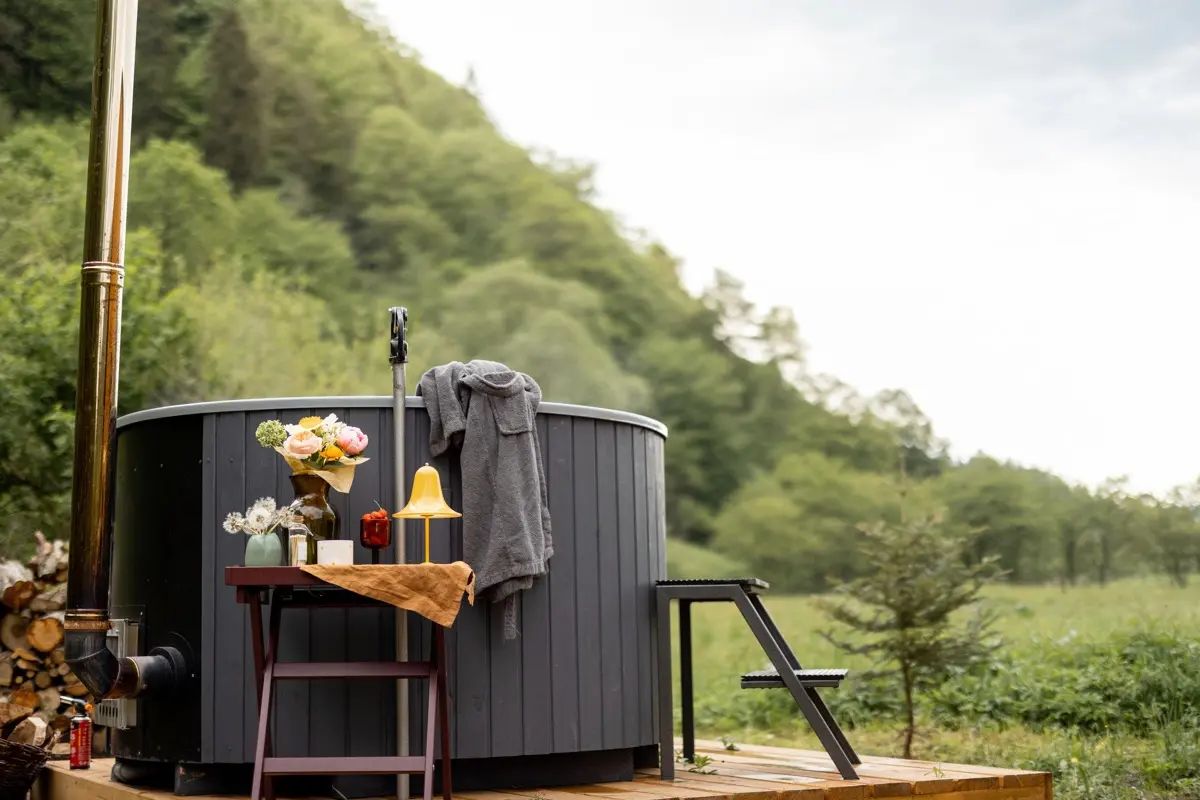 Wood-fired hot tub on a timber deck with woodland beyond