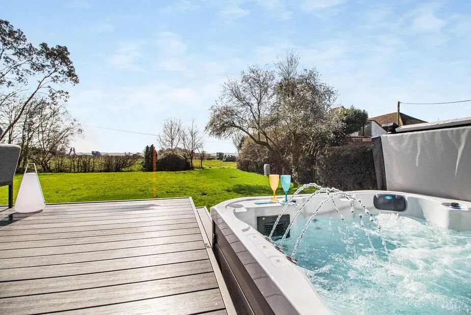 Hot tub with arcing water jets and two champagne flutes on the rim overlooking open fields