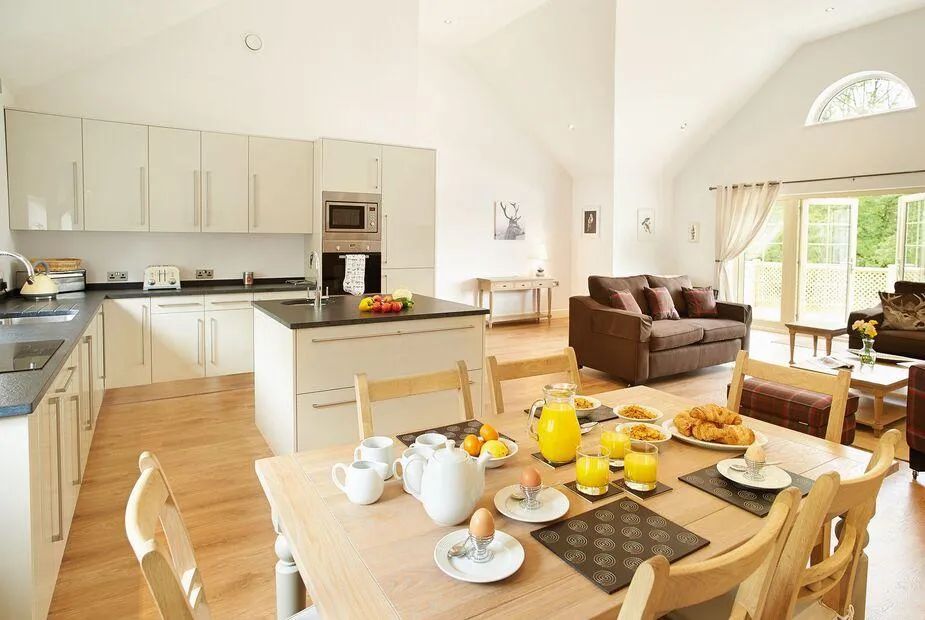 Open-plan kitchen and dining area with cream cabinets, dining table set for breakfast and French doors to the garden